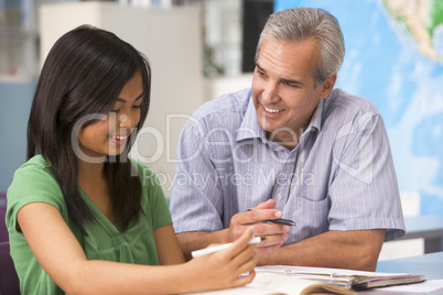 A teacher instructs a schoolgirl in a high school class