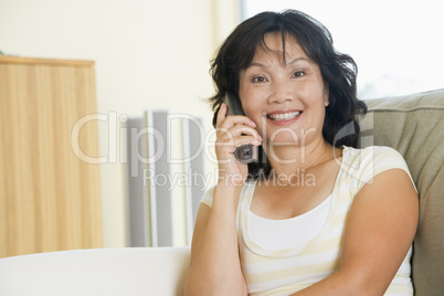 Woman sitting in living room using telephone and smiling