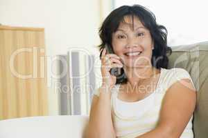 Woman sitting in living room using telephone and smiling