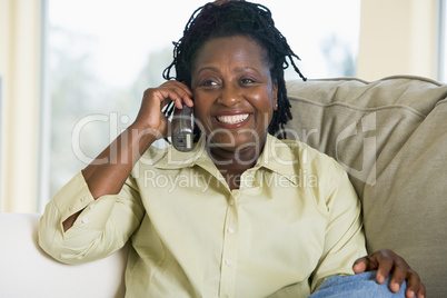 Woman sitting in living room using telephone and smiling