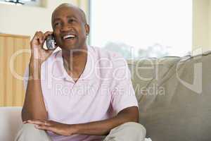 Man sitting in living room using telephone and smiling