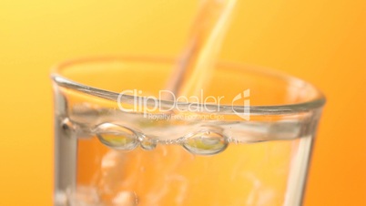 Pouring water in glass orange background