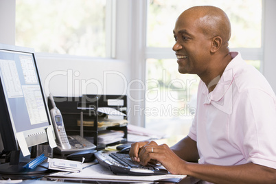 Man in home office using computer and smiling