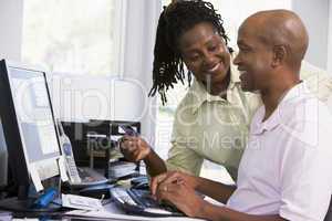Couple in home office with credit card using computer and smilin