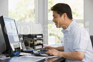 Man in home office using computer and smiling