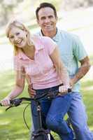 Couple on one bike outdoors smiling