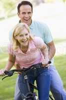 Couple on one bike outdoors smiling