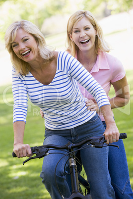 Two friends on one bike outdoors smiling