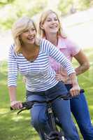 Two friends on one bike outdoors smiling