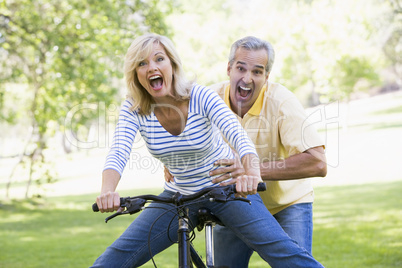 Couple on bike outdoors smiling and acting scared