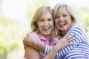 Two women outdoors hugging and smiling