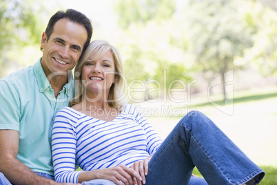 Couple relaxing outdoors in park smiling