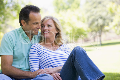 Couple relaxing outdoors in park smiling Couple relaxing outdoors in park smiling