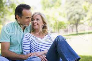 Couple relaxing outdoors in park smiling