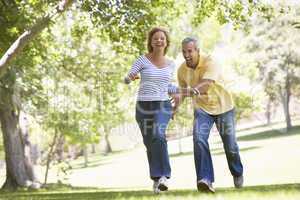 Couple running outdoors in park and smiling