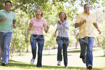 Two couples running outdoors smiling