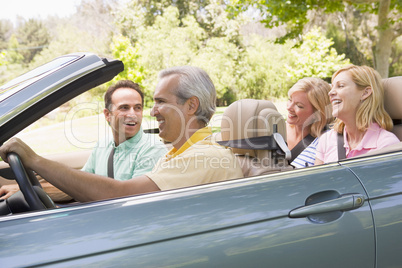 Two couples in convertible car smiling