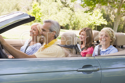 Family in convertible car smiling