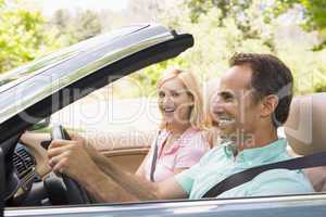 Couple in convertible car smiling