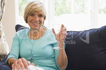 Woman sitting in living room with drink smiling