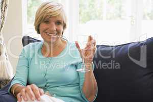 Woman sitting in living room with drink smiling