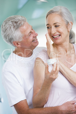 Couple embracing at a spa holding cream and smiling