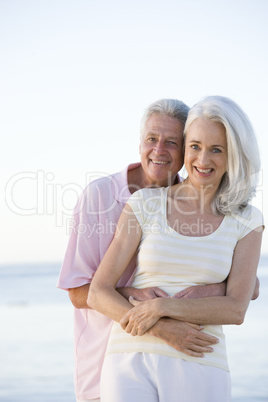 Couple at the beach embracing and smiling