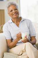 Woman sitting in living room with coffee smiling