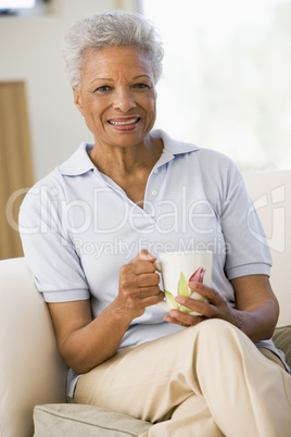 Woman sitting in living room with coffee smiling