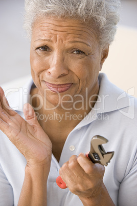 Woman holding wrench looking unsure