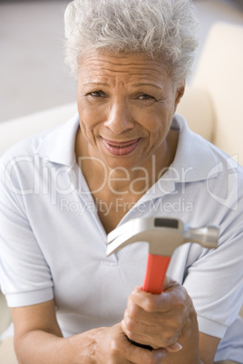 Woman holding hammer looking unsure