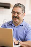 Man in kitchen with laptop smiling