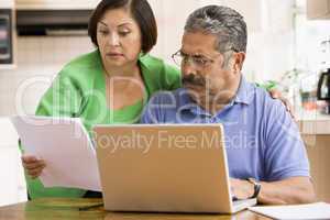 Couple in kitchen with laptop and paperwork