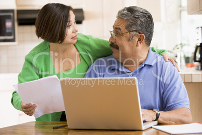 Couple in kitchen with laptop and paperwork