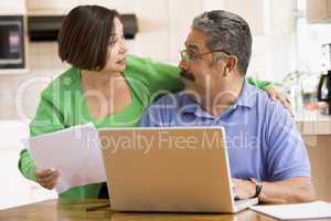 Couple in kitchen with laptop and paperwork