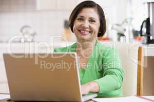 Woman in kitchen with laptop smiling