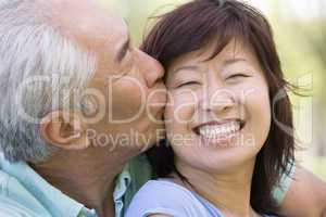 Couple relaxing outdoors in park kissing and smiling