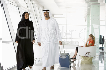 Couple walking through airport departure lounge