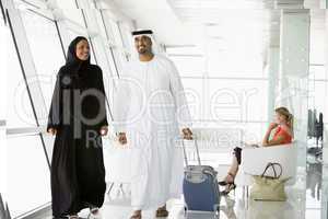 Couple walking through airport departure lounge