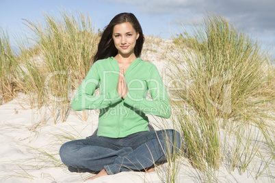 Young woman meditating amongst sand dunes