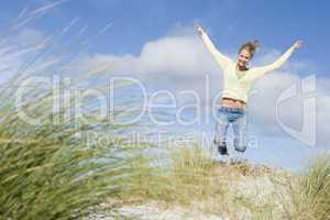 Young woman jumping amongst dunes
