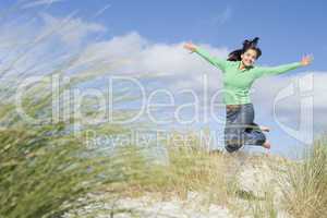 Young woman jumping amongst sand dunes