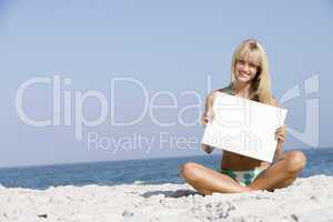 Woman on beach holding blank card
