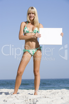 Woman on beach holding blank card