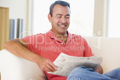 Man reading newspaper in living room smiling