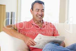 Man reading newspaper in living room smiling