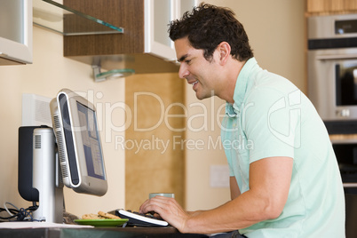 Man in kitchen using computer and smiling