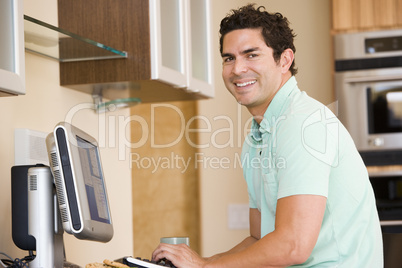 Man in kitchen using computer and smiling