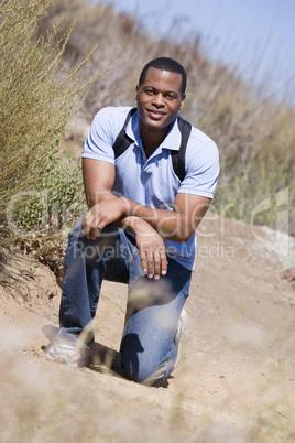 Man crouching on path to beach smiling