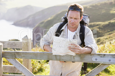 Man relaxing on cliffside path holding map